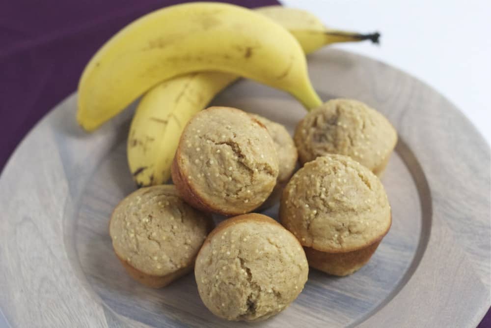 Banana millet muffins on a plate with bananas