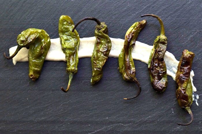 grilled shishito peppers on a slate board