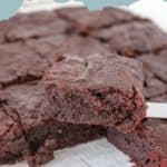 A close-up of fudgy brownies, with one rich slice being lifted out by a spatula. Text reads "Fudgy Brownies" at the top.