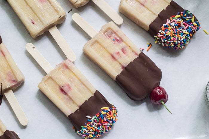 Vegan Banana Split Popsicles are made by blending coconut milk with ripe banana, then mixing with chopped fresh strawberries and pineapple.