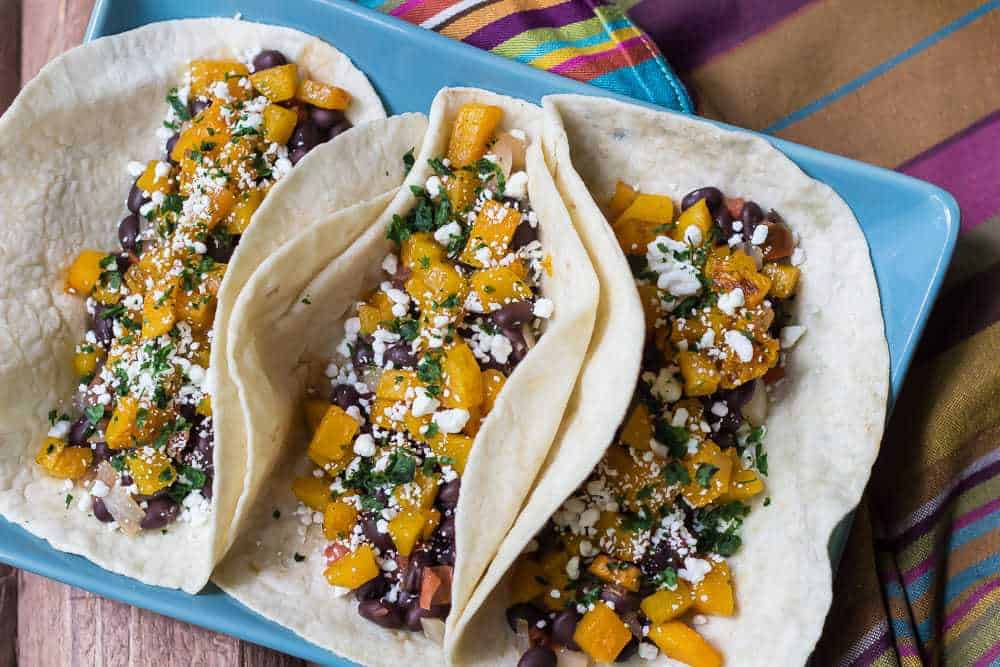 Butternut Squash Tacos - Butternut squash is cubed and roasted with spices, while black beans simmer with onion and tomato.