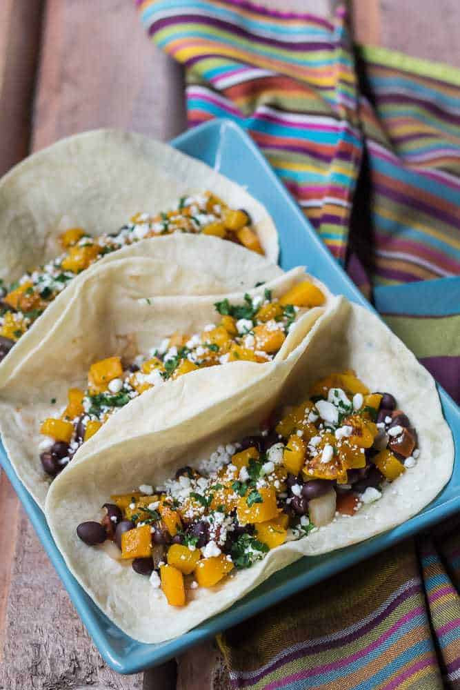 Butternut squash tacos are made with spiced roasted squash, black beans, and crumbled cheese.