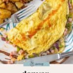 A classic Denver omelet filled with diced ham, green peppers, and onions is served alongside seasoned breakfast potatoes on a plate with a fork.