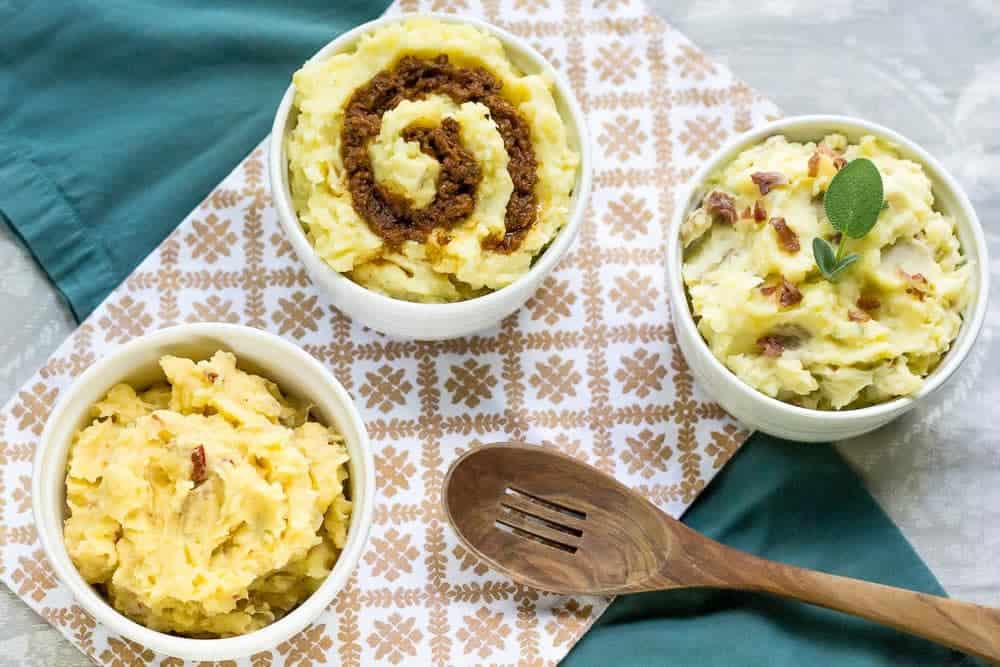 three flavors of mashed potatoes in white bowls