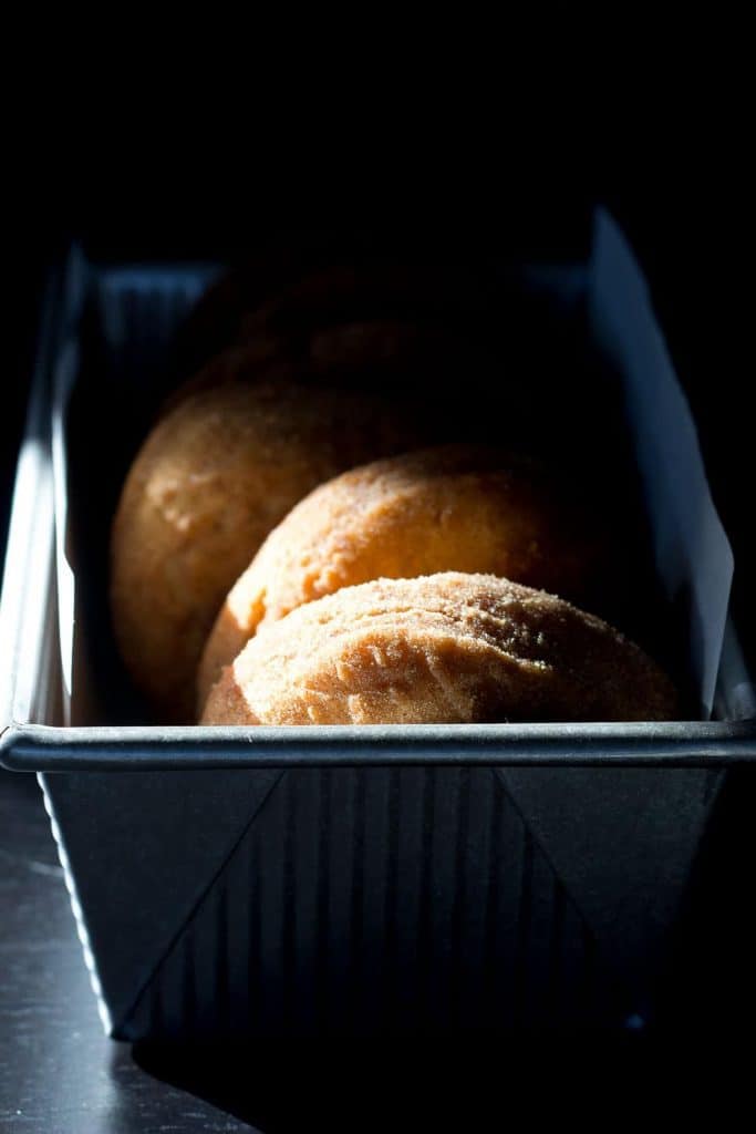 Sun shining on a pan of mashed potato donuts.