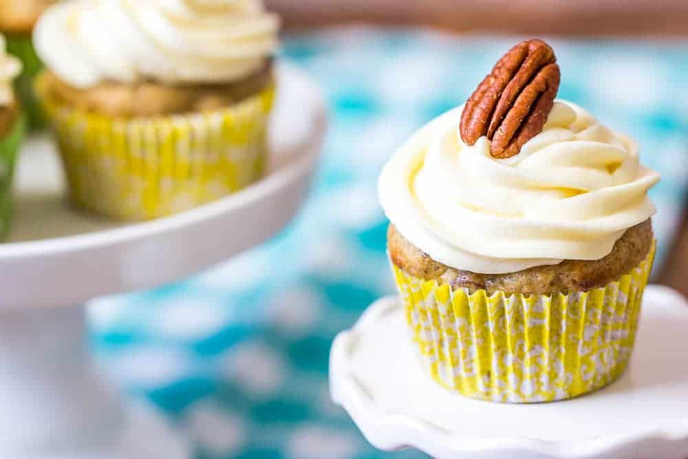 A cupcake with white frosting and a pecan on a mini cupcake stand.