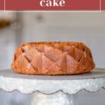A tomato cake bundt sits on a metal cake stand, with a label reading "tomato bundt cake" above and the website URL below.