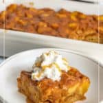 A slice of pumpkin bread pudding topped with whipped cream and caramel sauce is served on a white plate, with a baking dish of pumpkin bread pudding in the background.