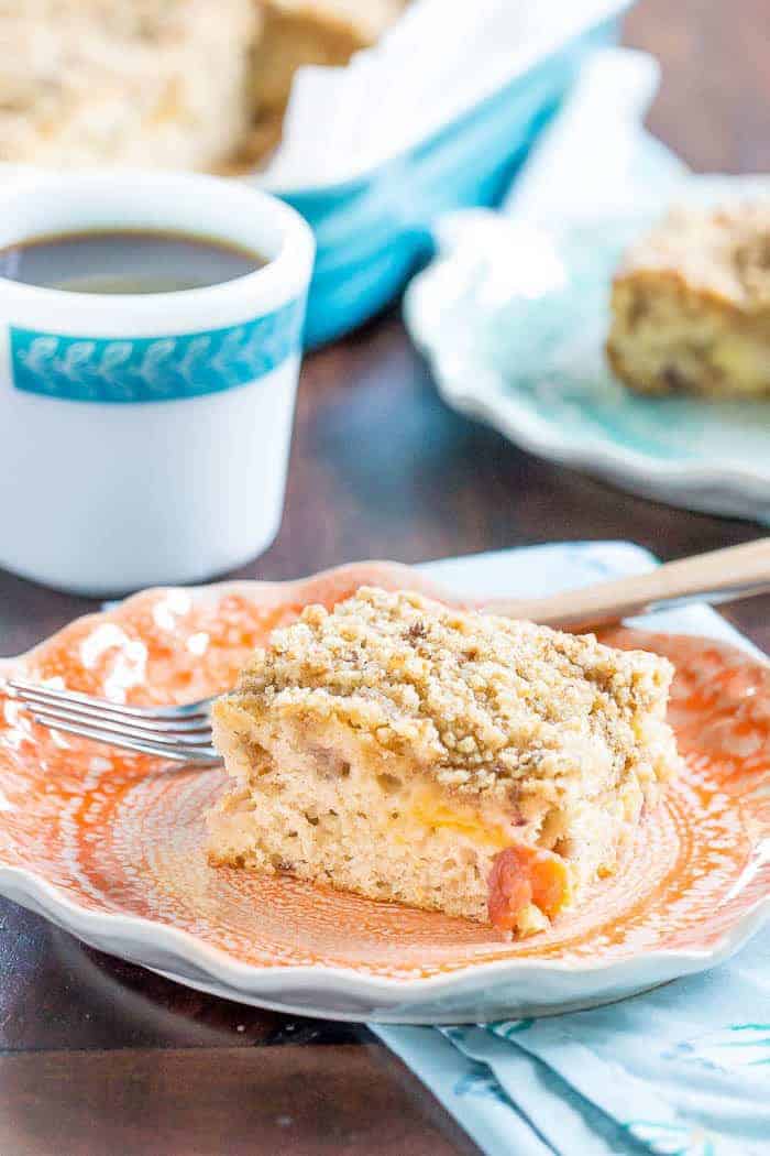 Slice of peach coffee cake on a peach colored plate.