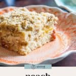 A slice of peach coffee cake with a crumb topping is served on a decorative plate, highlighting the sweet flavors of fresh peaches and cozy spices.