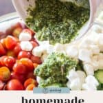 A bowl of cherry tomatoes, mozzarella balls, and cucumbers with rich walnut pesto being poured over them.