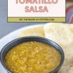 A bowl of zesty tomatillo salsa sits on a plate with crisp tortilla chips. Text overlay reads: "Tomatillo Salsa. Get the recipe at stetted.com.