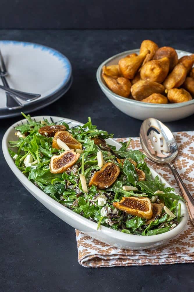 Salad with arugula, dried figs, and almonds, with plates and bowls