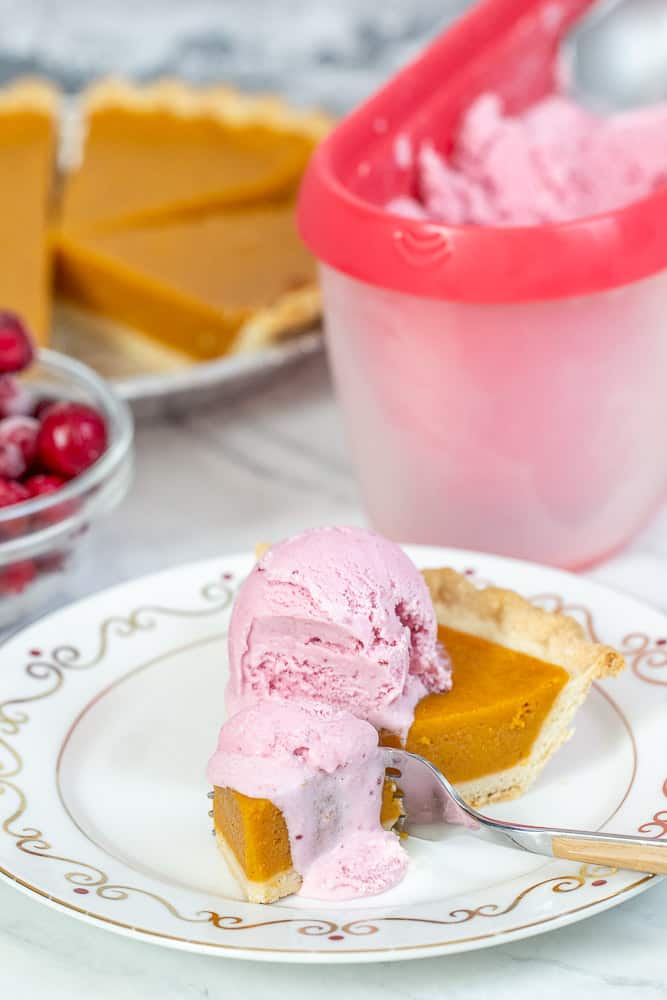 slice of pumpkin pie with cranberry ice cream on top, fork cutting into it