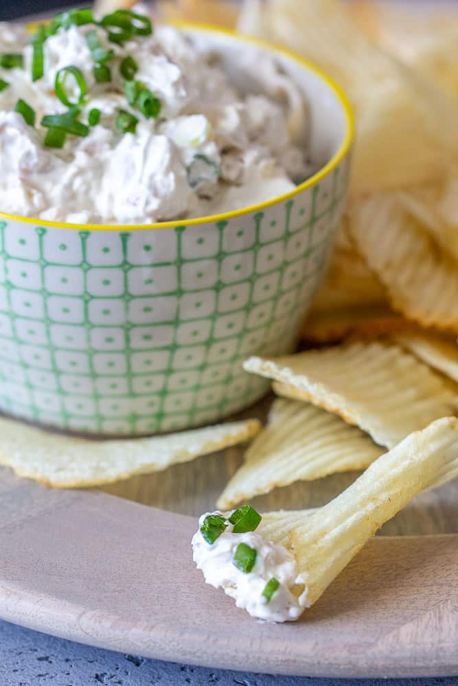 bacon onion dip on a chip with dip in background