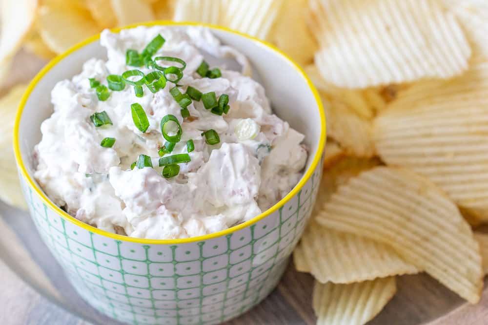Bacon onion dip in a bowl with chips.