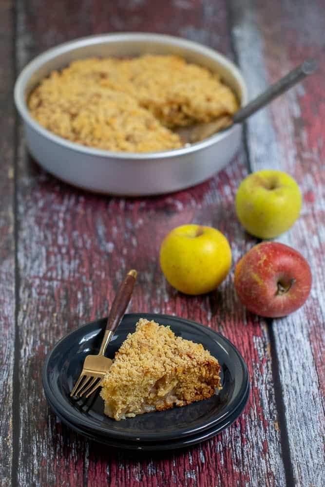 Apple coffee cake with a slice on a plate and apples