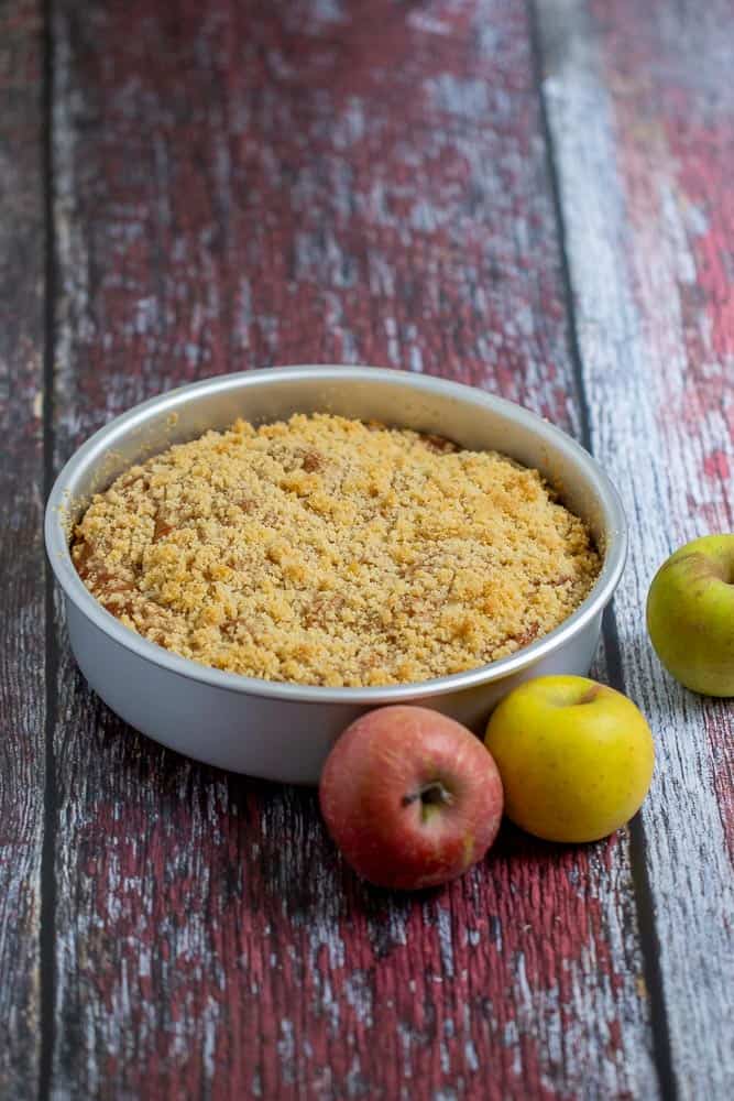 whole apple coffee cake on red wood with apples