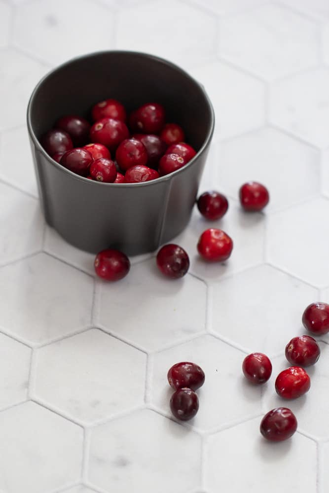 cranberries in black bowl with some loose on table