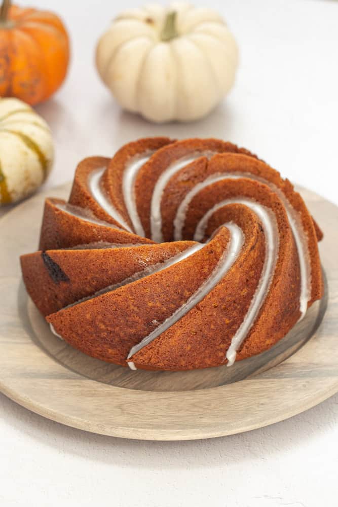 Pumpkin bundt cake in a swirl shape with glaze, and pumpkins in the background