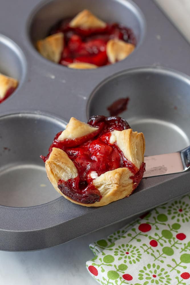 sugar plum cheese danish being removed from a muffin tin