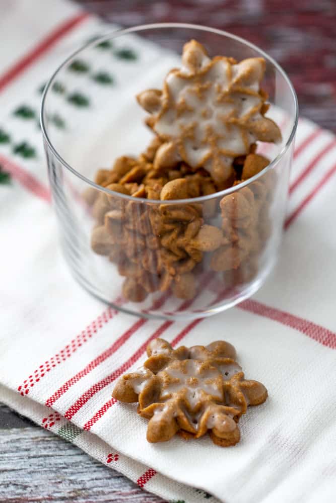 snowflake spritz cookies in a glass on a napkin, one outside of the glass