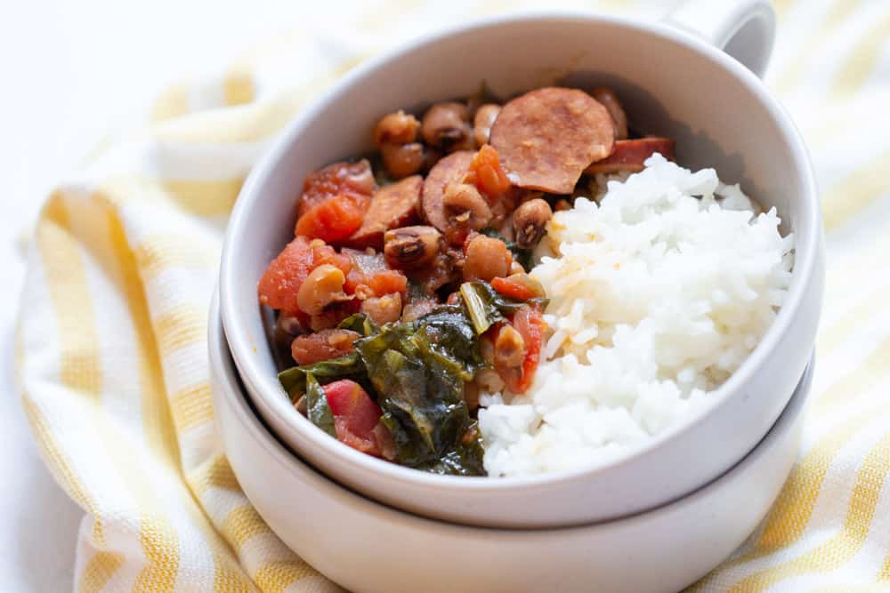 black eyed peas, sausage, tomatoes, greens, and rice in a stacked bowl