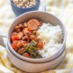 black eyed peas, sausage, tomatoes, greens, and rice in a bowl with dried peas behind