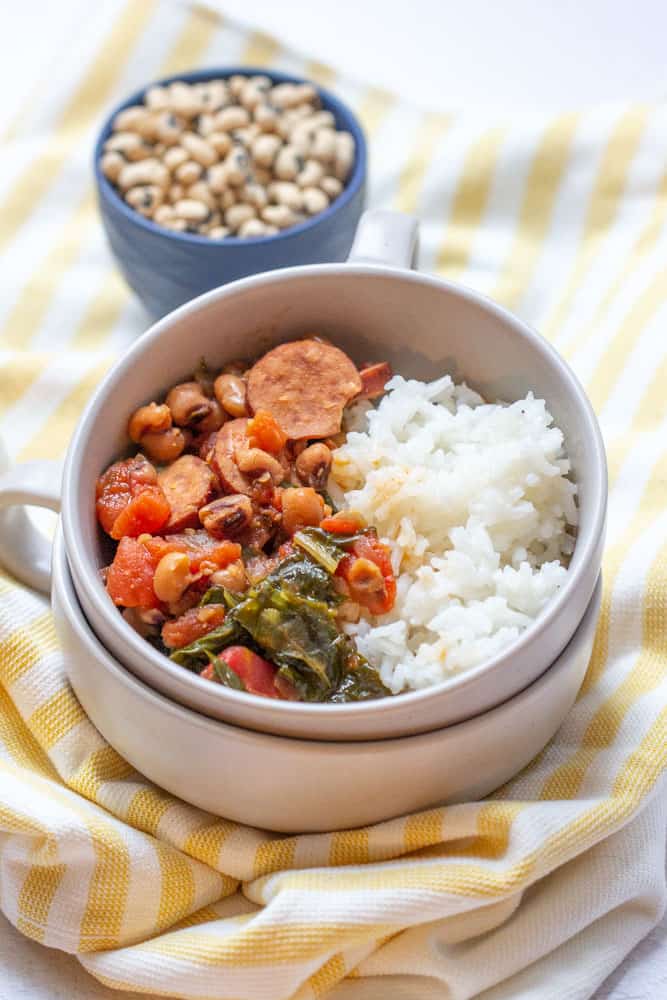 black eyed peas, sausage, tomatoes, greens, and rice in a bowl with dried peas behind