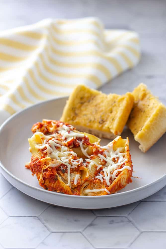stuffed pasta shells with chicken on a plate with garlic bread slices