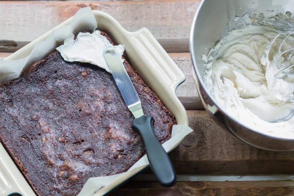 brownies being frosted with white frosting, overhead