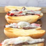 open steak and cheese sandwiches on a baking sheet for broiling
