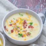 close up of baked potato soup in a shallow mug with toppings