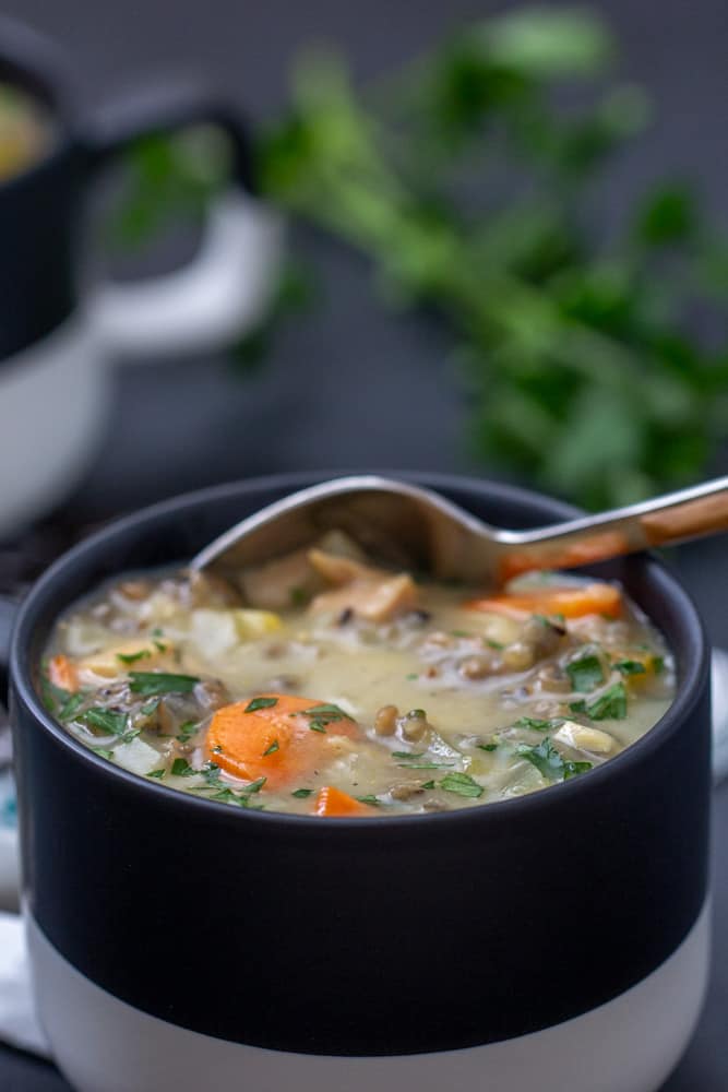 spoon scooping up chicken wild rice soup out of a black and white mug