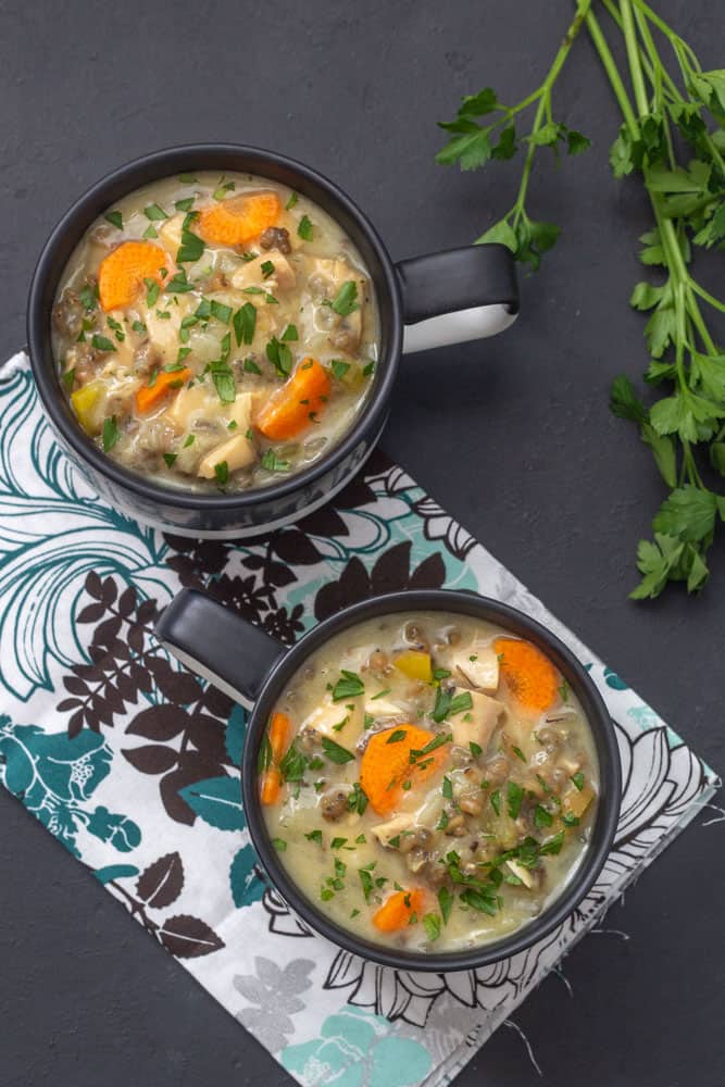 overhead of chicken wild rice soup in black mugs with a floral napkin