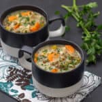 chicken wild rice soup in black and white mugs with a floral napkin on a black countertop