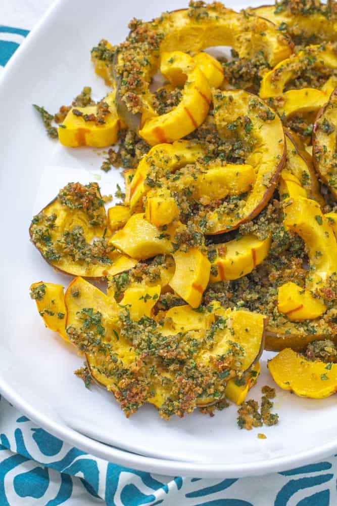 roasted winter squash with garlic herb topping on a platter with a blue and white napkin