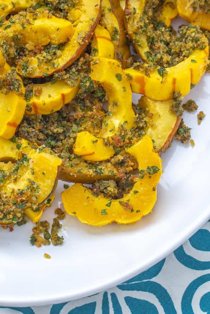 close up roasted winter squash with garlic herb topping on a platter