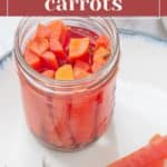 A jar of tangy pickled carrots sits on a white plate, with sliced carrots beside it, showcasing the delicious results of mastering how to pickle carrots.