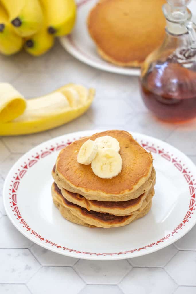 banana bread pancakes with bananas on top, banana and syrup behind