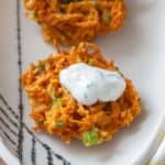 close up of carrot fritter with yogurt sauce on top