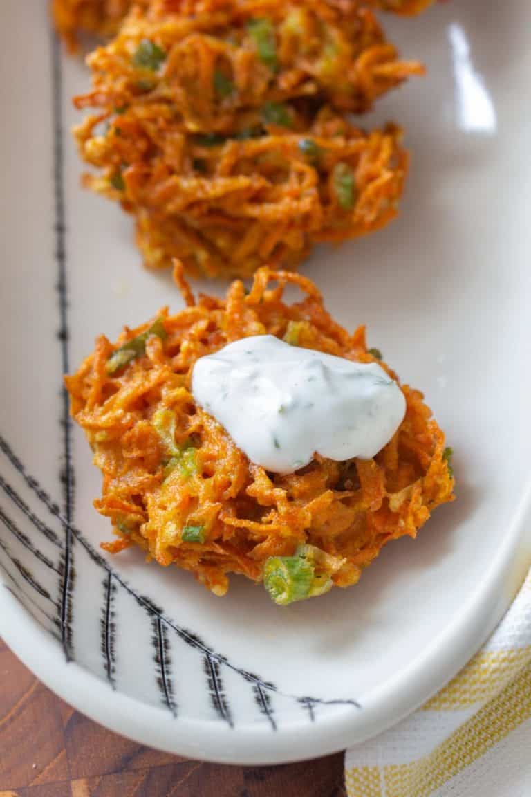 close up of carrot fritter with yogurt sauce on top