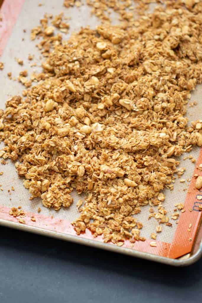 peanut butter granola on a silicone liner on a sheet pan