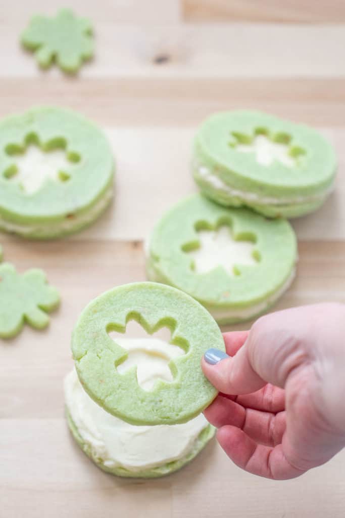 hand placing cut out cookie on top of pistachio pudding cookie
