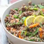 gray serving dish of quinoa primavera with lemon slices on top