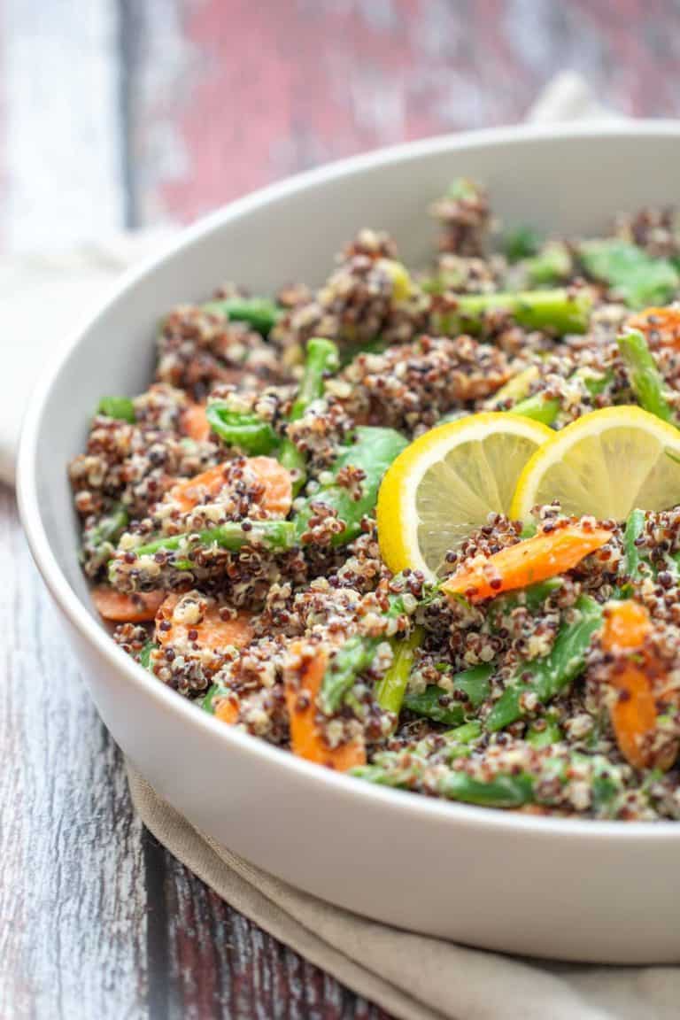 gray serving dish of quinoa primavera with lemon slices on top