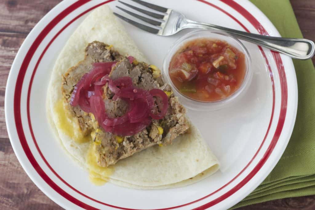 taco meatloaf on a tortilla with salsa and pickled onions