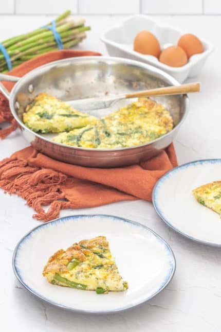 sliced asparagus dill frittata on white plates with serving pan