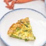slice of asparagus dill frittata on a white plate with blue rim