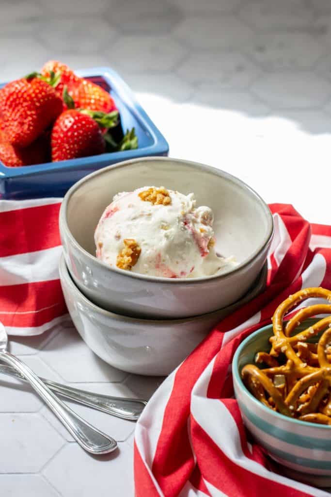 strawberry pretzel ice cream with bowls of pretzels and strawberries